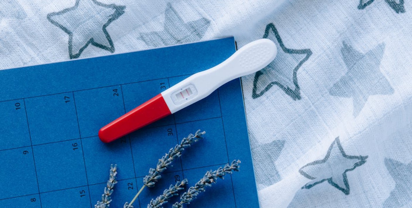 image of positive pregnancy test on top of calendar