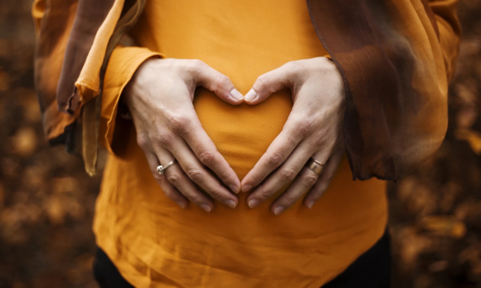 Stomach of pregnant woman with hands making heart sign